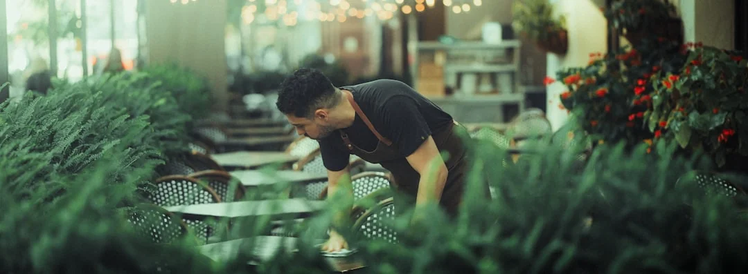 Person using spray bottle and cloth for cleaning a kitchen shelf, ensuring hygiene and cleanliness.